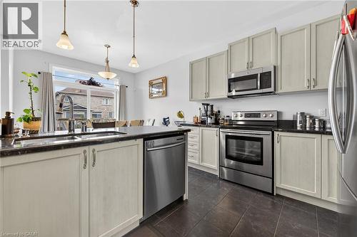 The kitchen features light-toned cabinetry, dark countertops, and stainless steel appliances including a range, microwave, and dishwasher - 44 Matteo Trail, Hamilton, ON - Indoor Photo Showing Kitchen With Double Sink