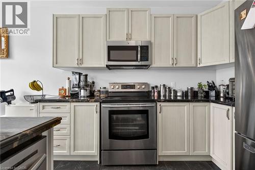 The kitchen features light-colored cabinetry, dark countertops, a stainless steel range, and a matching microwave - 44 Matteo Trail, Hamilton, ON - Indoor Photo Showing Kitchen