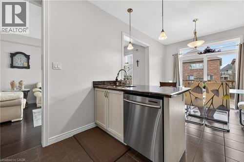 The kitchen features a functional island with a sink, a stainless steel dishwasher, and dark granite countertops - 44 Matteo Trail, Hamilton, ON - Indoor Photo Showing Kitchen
