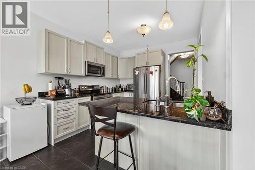 The kitchen features light-colored cabinetry, dark countertops, and stainless steel appliances - 44 Matteo Trail, Hamilton, ON - Indoor Photo Showing Kitchen
