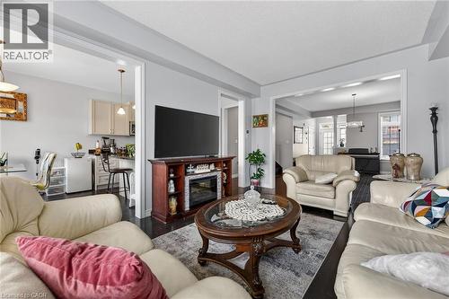 The living area features dark flooring, light-colored walls, and a decorative fireplace with a mantel - 44 Matteo Trail, Hamilton, ON - Indoor Photo Showing Living Room