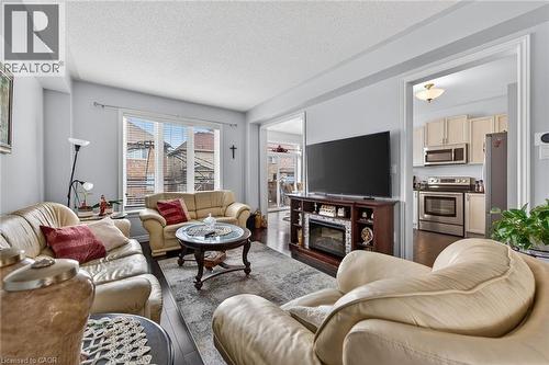 Living room featuring dark wood flooring, a decorative rug, and a large window with blinds - 44 Matteo Trail, Hamilton, ON - Indoor Photo Showing Living Room