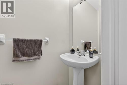 Bathroom featuring a pedestal sink with a chrome faucet and a wall-mounted mirror - 44 Matteo Trail, Hamilton, ON - Indoor Photo Showing Bathroom