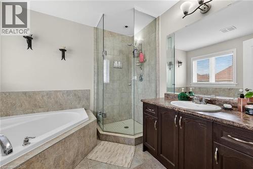Bathroom featuring a large corner tub, a glass-enclosed shower, a vanity with a built-in sink, and a window with blinds - 44 Matteo Trail, Hamilton, ON - Indoor Photo Showing Bathroom