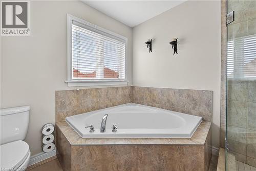 Bathroom featuring a built-in corner tub with tiled surround, a window with blinds, and a glass-enclosed shower - 44 Matteo Trail, Hamilton, ON - Indoor Photo Showing Bathroom