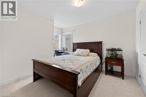 This room features neutral-toned walls, light-colored carpeting, and a window with blinds providing natural light - 44 Matteo Trail, Hamilton, ON - Indoor Photo Showing Bedroom