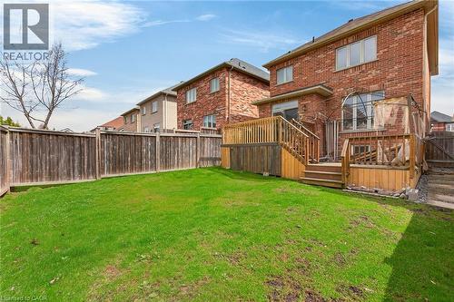 The property features a brick exterior and a wooden deck with stairs leading down to a fenced yard - 44 Matteo Trail, Hamilton, ON - Outdoor With Deck Patio Veranda