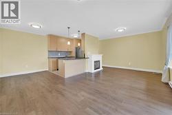 Open concept living area featuring wood flooring, light-colored walls, and crown molding - 