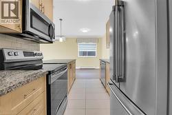 Kitchen featuring stainless steel appliances, light wood cabinetry, and granite countertops - 