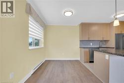 Living area featuring hardwood style flooring, a window with blinds, and light-colored walls - 
