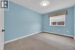 Room with light blue walls and neutral-toned carpet, featuring a window with horizontal blinds and a valance - 