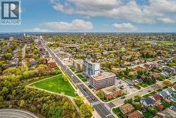 This aerial view showcases a vibrant community featuring extensive green spaces, a main thoroughfare, and a mix of residential and commercial properties - 