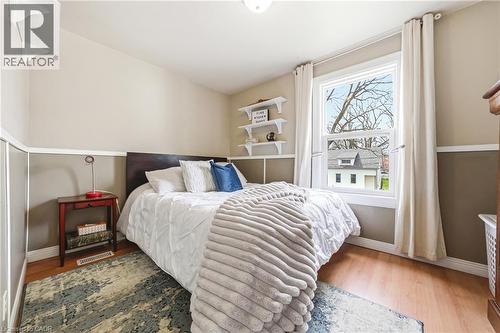 This inviting room features hardwood floors, a large window providing natural light, and a two-toned wall with wainscoting - 30 Grand Avenue, Caledonia, ON - Indoor Photo Showing Bedroom