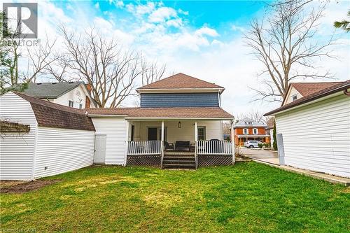 The property features a spacious lawn, a rear covered porch with railings, and a white detached shed - 30 Grand Avenue, Caledonia, ON - Outdoor With Deck Patio Veranda