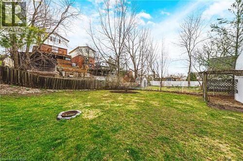 Spacious backyard featuring a lush lawn, a stone fire pit, and a wooden privacy fence - 30 Grand Avenue, Caledonia, ON - Outdoor
