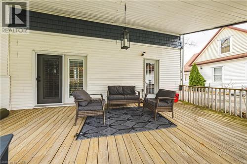 Expansive covered deck featuring light-toned wooden flooring, a textured black accent wall, and a hanging lantern light fixture - 30 Grand Avenue, Caledonia, ON - Outdoor With Deck Patio Veranda With Exterior