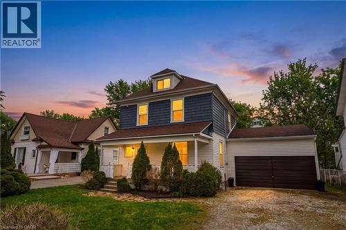Two-story property featuring a covered front porch with white columns, a dormer window, and an attached garage with a dark wood-finish garage door - 30 Grand Avenue, Caledonia, ON 