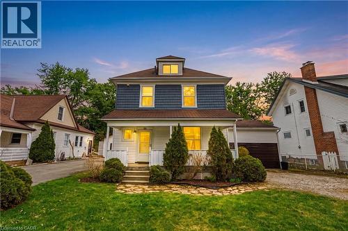 Two-story residence featuring a covered front porch, dormer window, and shingle siding on the upper level - 30 Grand Avenue, Caledonia, ON 