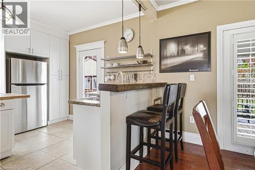 The kitchen features white cabinetry, stainless steel appliances, and a breakfast bar with seating - 30 Grand Avenue, Caledonia, ON 