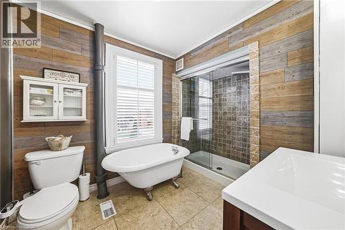 The bathroom features a clawfoot tub, a separate shower with tiled walls and a glass enclosure, and a vanity with a white countertop - 30 Grand Avenue, Caledonia, ON 