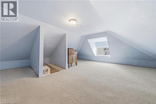 Spacious attic space featuring light blue walls, a window, and light-colored carpet - 30 Grand Avenue, Caledonia, ON 