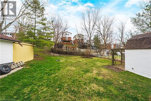 The property features a spacious yard with a green lawn, a white storage shed with a brown roof, and a yellow shed with a brown roof - 30 Grand Avenue, Caledonia, ON 