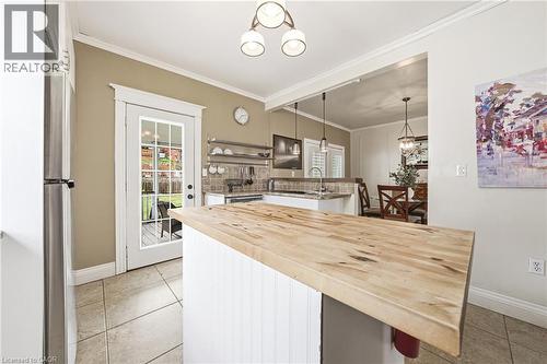 The kitchen features a wooden island countertop, tiled flooring, and a stainless steel refrigerator - 30 Grand Avenue, Caledonia, ON - Indoor Photo Showing Other Room