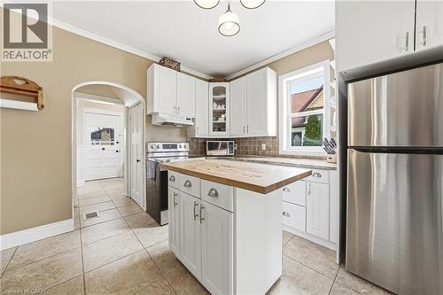 The kitchen features white cabinetry, a central island with a wood countertop, and stainless steel appliances including a refrigerator and range - 30 Grand Avenue, Caledonia, ON - Indoor Photo Showing Kitchen