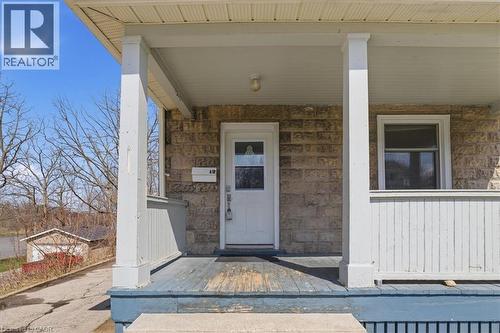 Welcoming front porch featuring a white door with glass panels, a stone exterior, and white column supports - 12 Todd Street, Cambridge, ON - Outdoor With Exterior