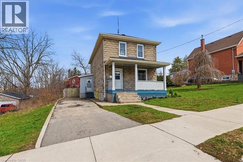 This property features a stone exterior and a covered front porch, offering a welcoming facade - 12 Todd Street, Cambridge, ON - Outdoor With Deck Patio Veranda