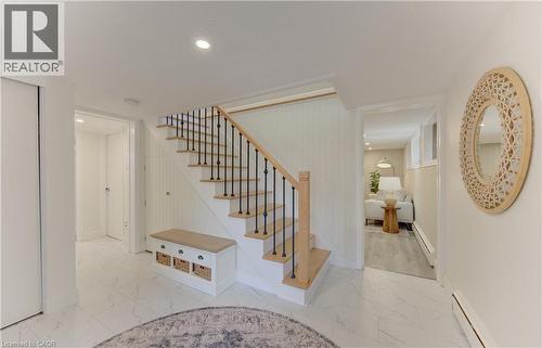 This property features a bright staircase with natural wood treads and handrail, complemented by black iron balusters - 400 Manchester Road, Kitchener, ON - Indoor Photo Showing Other Room