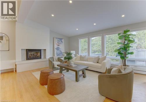 The property features an inviting living room with hardwood floors, a white brick fireplace, and recessed lighting - 400 Manchester Road, Kitchener, ON - Indoor Photo Showing Living Room With Fireplace