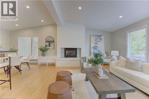 The expansive living area features hardwood floors, recessed lighting, and a prominent fireplace with a light-colored surround - 400 Manchester Road, Kitchener, ON - Indoor Photo Showing Other Room With Fireplace