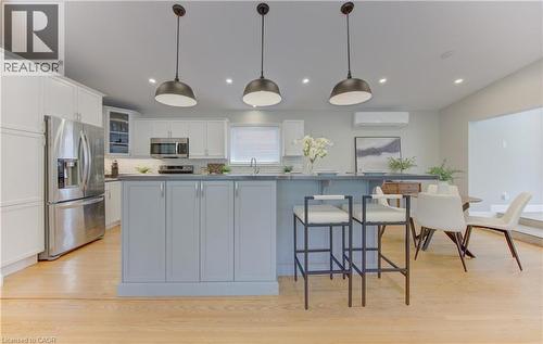 Open concept kitchen featuring an island with seating, pendant lighting, stainless steel appliances, and light hardwood floors - 400 Manchester Road, Kitchener, ON - Indoor