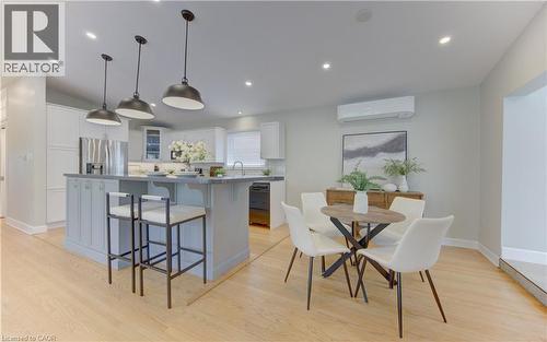 Kitchen and dining area featuring light wood flooring, an island with pendant lighting, white cabinetry, and stainless steel appliances - 400 Manchester Road, Kitchener, ON - Indoor Photo Showing Dining Room