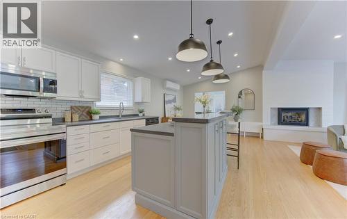 This inviting open-concept space features a modern kitchen with white cabinetry, stainless steel appliances, and a tiled backsplash - 400 Manchester Road, Kitchener, ON - Indoor Photo Showing Kitchen With Upgraded Kitchen