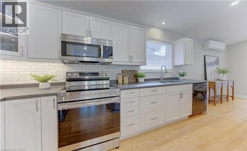 The kitchen features white cabinetry, stainless steel appliances, and a subway tile backsplash - 400 Manchester Road, Kitchener, ON - Indoor Photo Showing Kitchen With Double Sink
