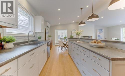 The kitchen features light wood flooring, white cabinetry with silver hardware, a double basin sink with a modern faucet, and pendant lighting - 400 Manchester Road, Kitchener, ON - Indoor Photo Showing Kitchen With Double Sink