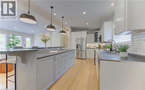 The kitchen features hardwood floors, white cabinetry, a large island with a grey countertop, and stainless steel appliances including a refrigerator and dishwasher - 400 Manchester Road, Kitchener, ON - Indoor Photo Showing Kitchen With Upgraded Kitchen