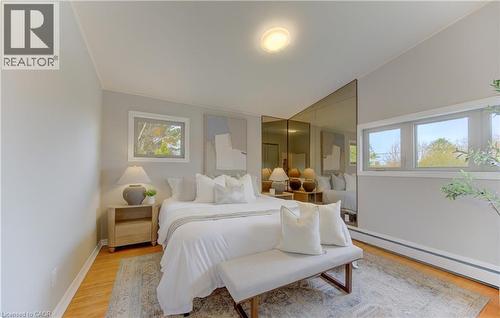 This inviting room features warm wood flooring, ample natural light from multiple windows, and a vaulted ceiling - 400 Manchester Road, Kitchener, ON - Indoor Photo Showing Bedroom