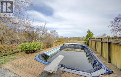 The property features an outdoor swimming pool with a diving board, surrounded by a wooden deck and a privacy fence - 400 Manchester Road, Kitchener, ON - Outdoor