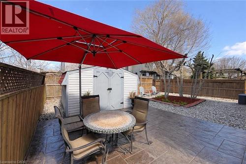 The property features a private outdoor area with stamped concrete patio, a red patio umbrella, and a storage shed - 21 Arden Avenue, Hamilton, ON 