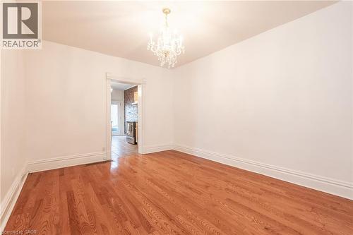 This room features hardwood floors, white walls, and a decorative chandelier - 198 Bay Street N, Hamilton, ON - Indoor Photo Showing Other Room