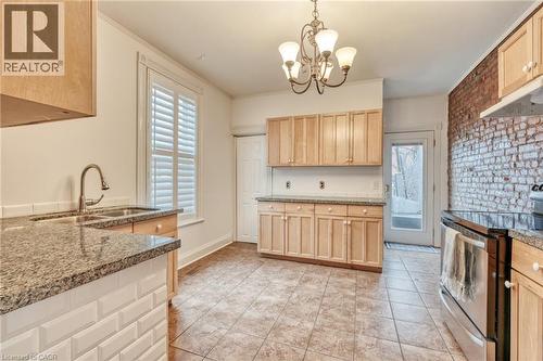 The kitchen features granite countertops, light wood cabinetry, and a tiled floor - 198 Bay Street N, Hamilton, ON - Indoor Photo Showing Kitchen With Double Sink