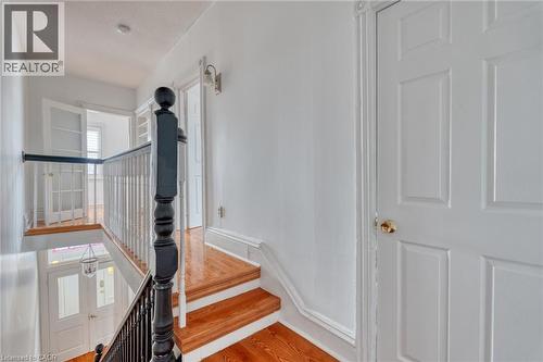 The property features hardwood stairs with a dark-stained handrail and white balusters - 198 Bay Street N, Hamilton, ON - Indoor Photo Showing Other Room