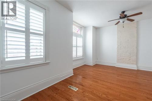 Room featuring hardwood floors, white walls, and white plantation shutters on the windows - 198 Bay Street N, Hamilton, ON - Indoor Photo Showing Other Room