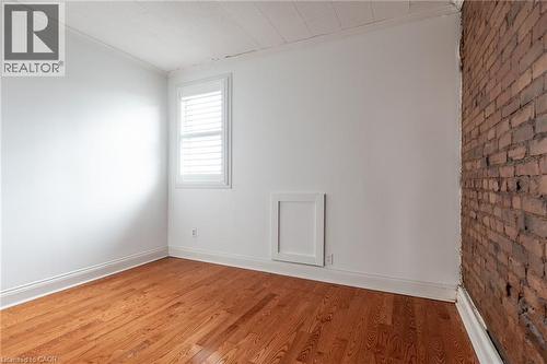 This room features hardwood flooring, white walls, and a window with white louvered shutters - 198 Bay Street N, Hamilton, ON - Indoor Photo Showing Other Room