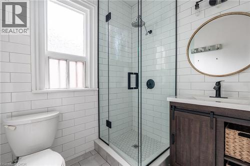 Bathroom with white subway tile walls, a glass-enclosed shower featuring a rain shower head, and a vanity with a white countertop and dark wood cabinetry - 198 Bay Street N, Hamilton, ON - Indoor Photo Showing Bathroom