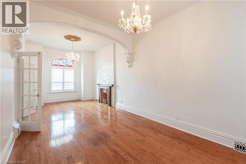 This room features hardwood floors, white walls, and an arched entryway with decorative corbels - 198 Bay Street N, Hamilton, ON - Indoor Photo Showing Other Room