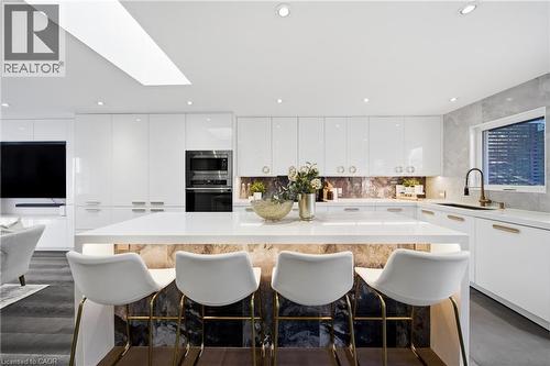 The kitchen features white cabinetry, a large center island with seating, integrated appliances, and recessed lighting - 2467 Bonner Road, Mississauga, ON - Indoor
